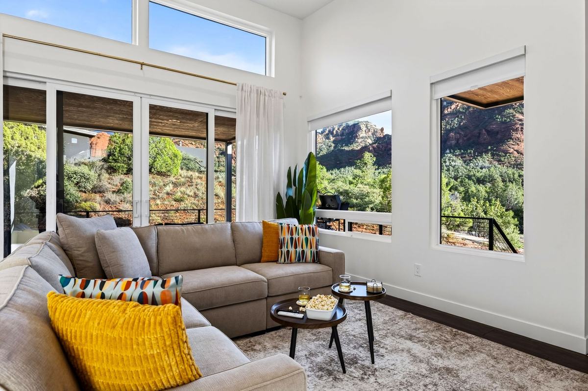 Living room with a large sectional and tall windows facing the red rocks.